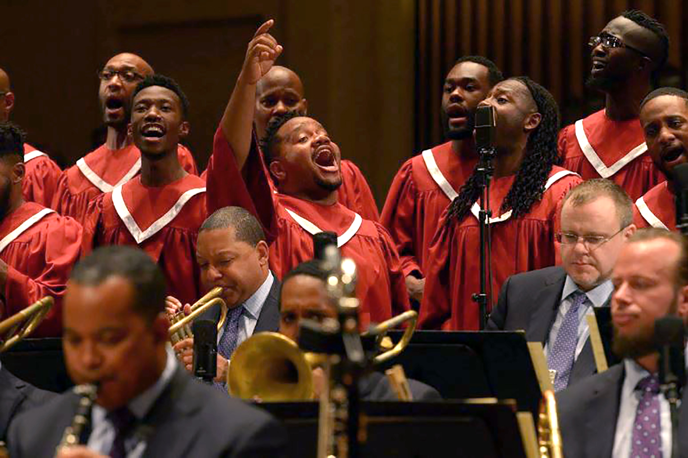 Jim Rawlins sings passionately with arm in the air in the middle of a gospel choir.