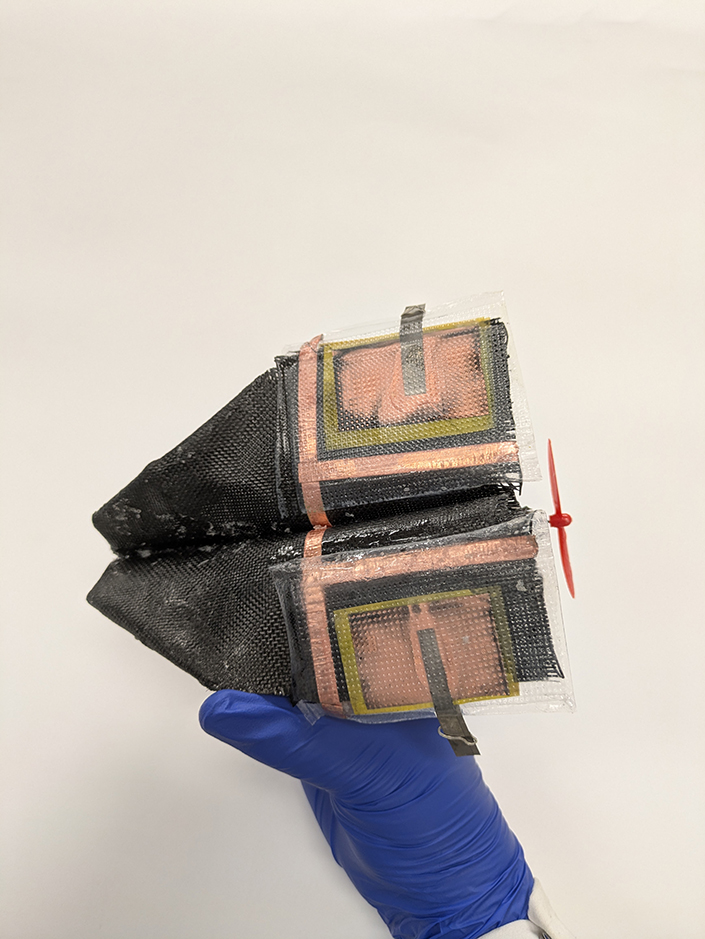 Black folded mini airplane with copper foils on the wings and small propeller.