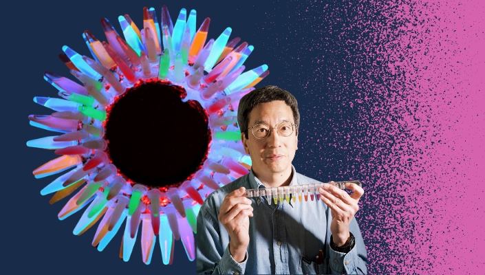 Wreath-style arrangement of GFP vials with photo of Roger Tsien in front and pink spray accent against blue background