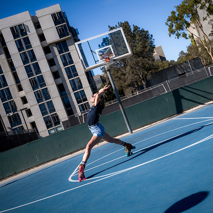 Student looks to the sky while roller skating on basketball court