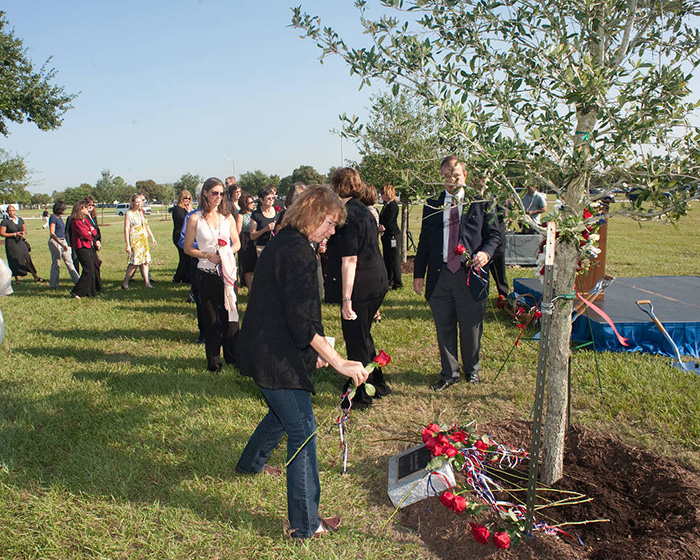 astronaut Sandra Magnus places a rose at a tree planted in Sally’s memory.