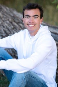 A college student sitting in front of a tree posing