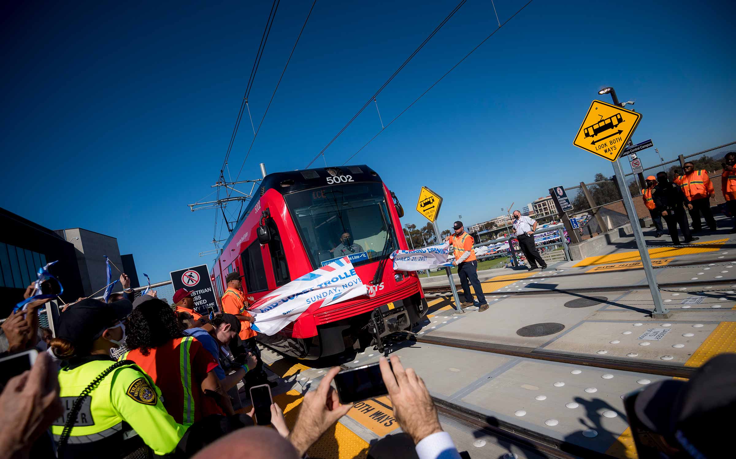 Blue line trolley burst through a banner at the UC San Diego Central Campus station.