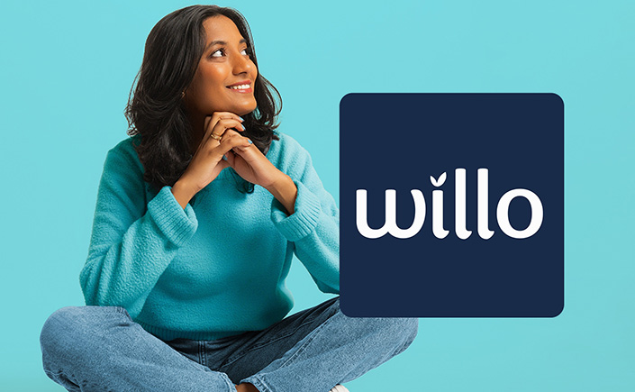 Girl sits with hands folded against blue background, beside 