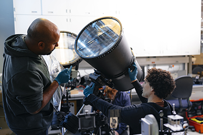 two male students looking at a telescope