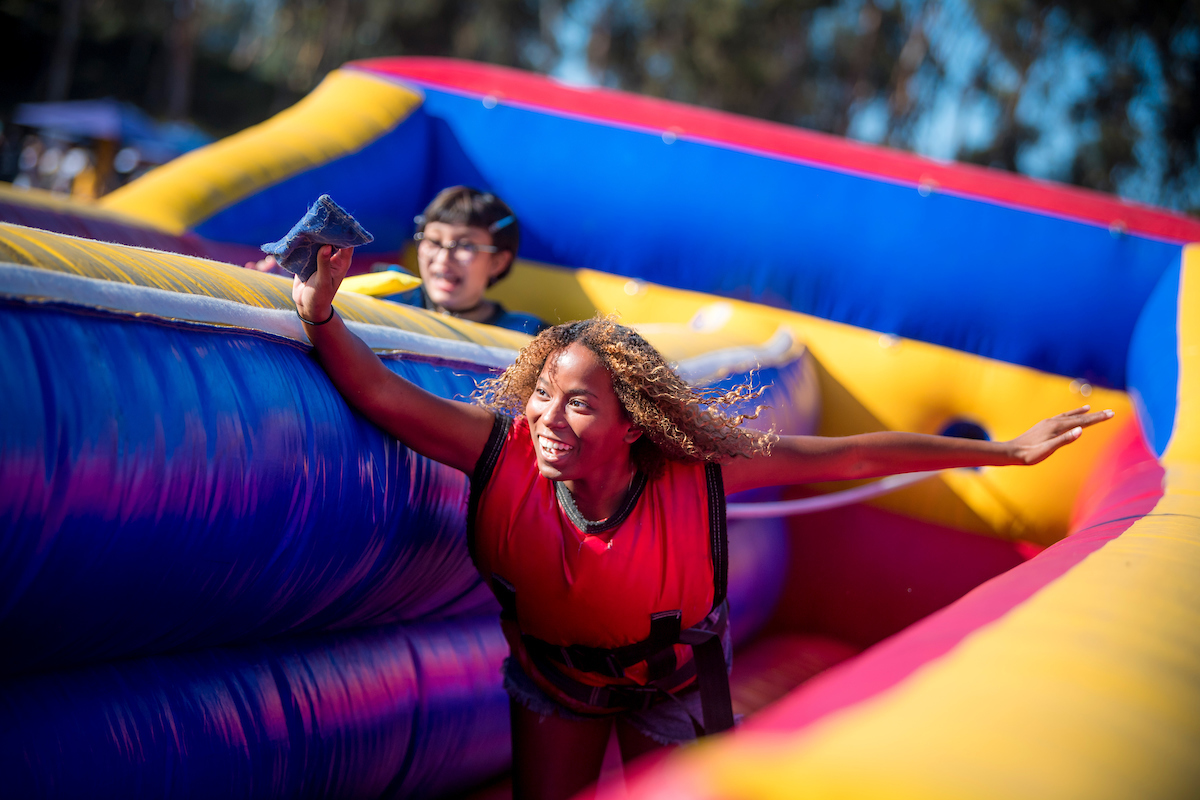 Woman running on an inflatable course reaching her hand out to touch the finish line.