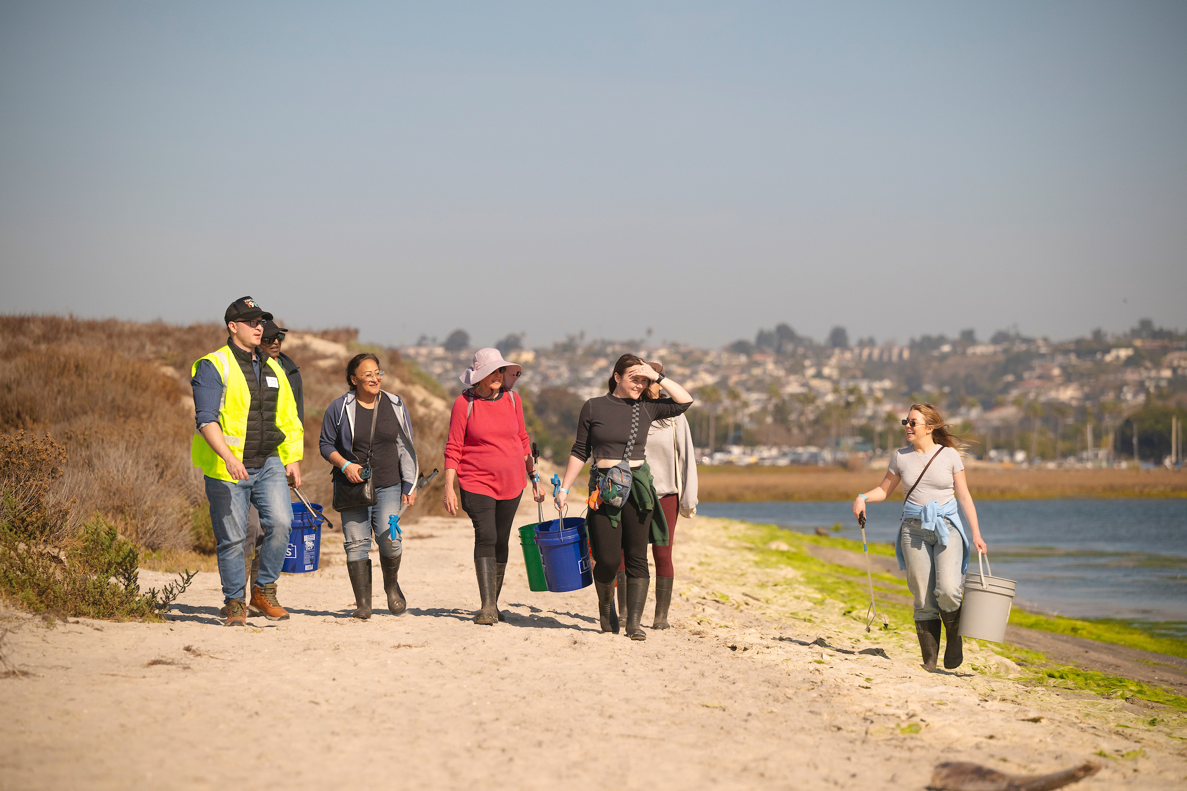 Volunteers walk marsh picking up trash.