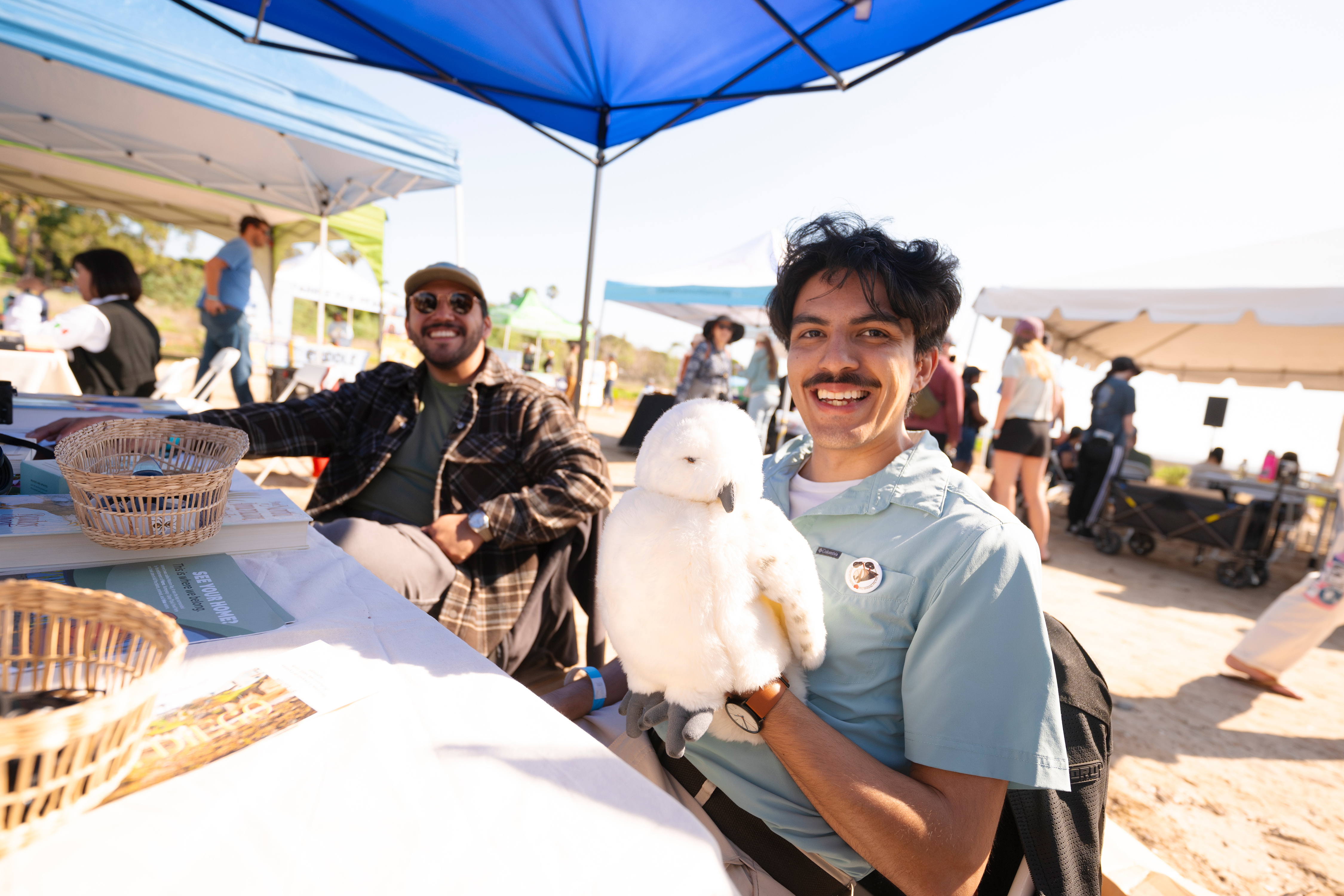 Person at a booth holds a white bird puppet.
