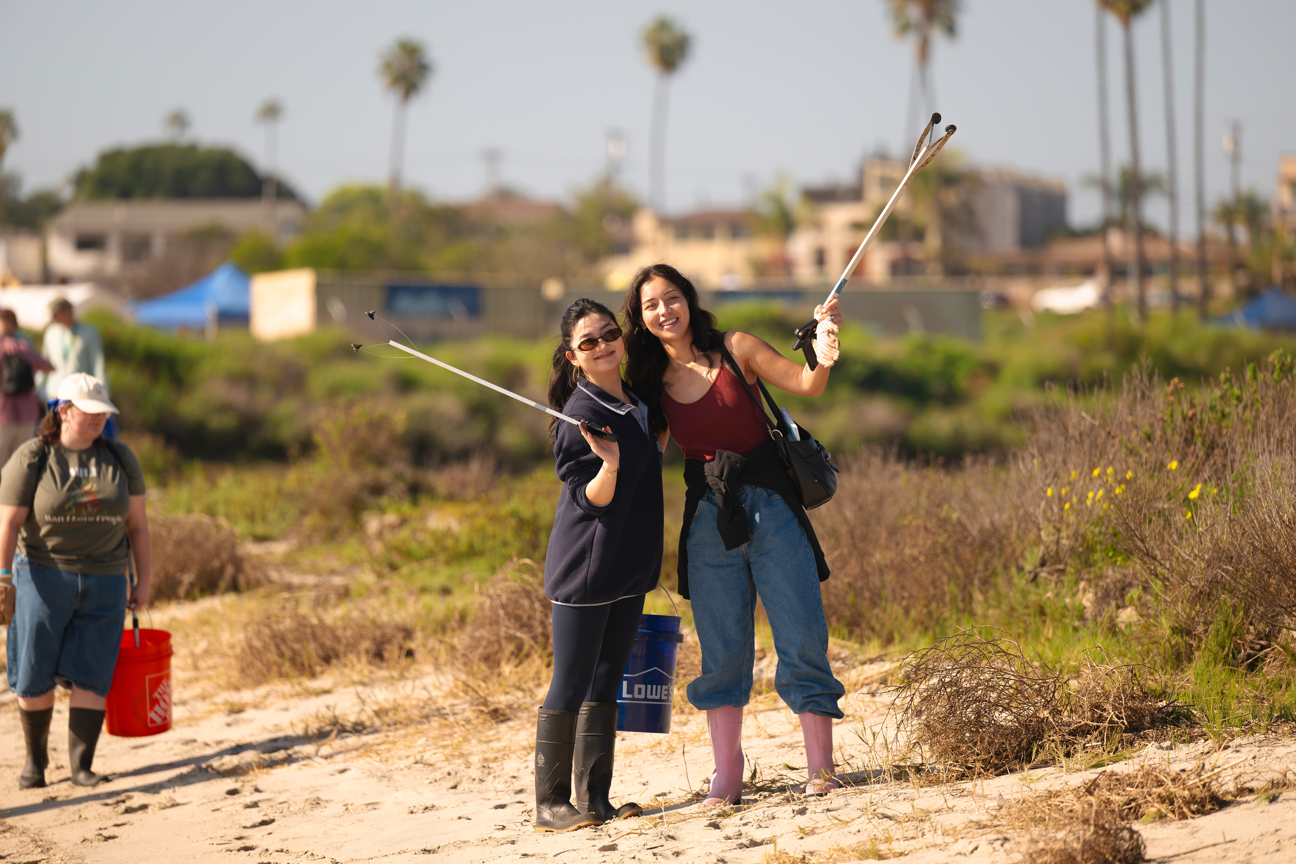 Two people pose near the water while on trash pick up duty.