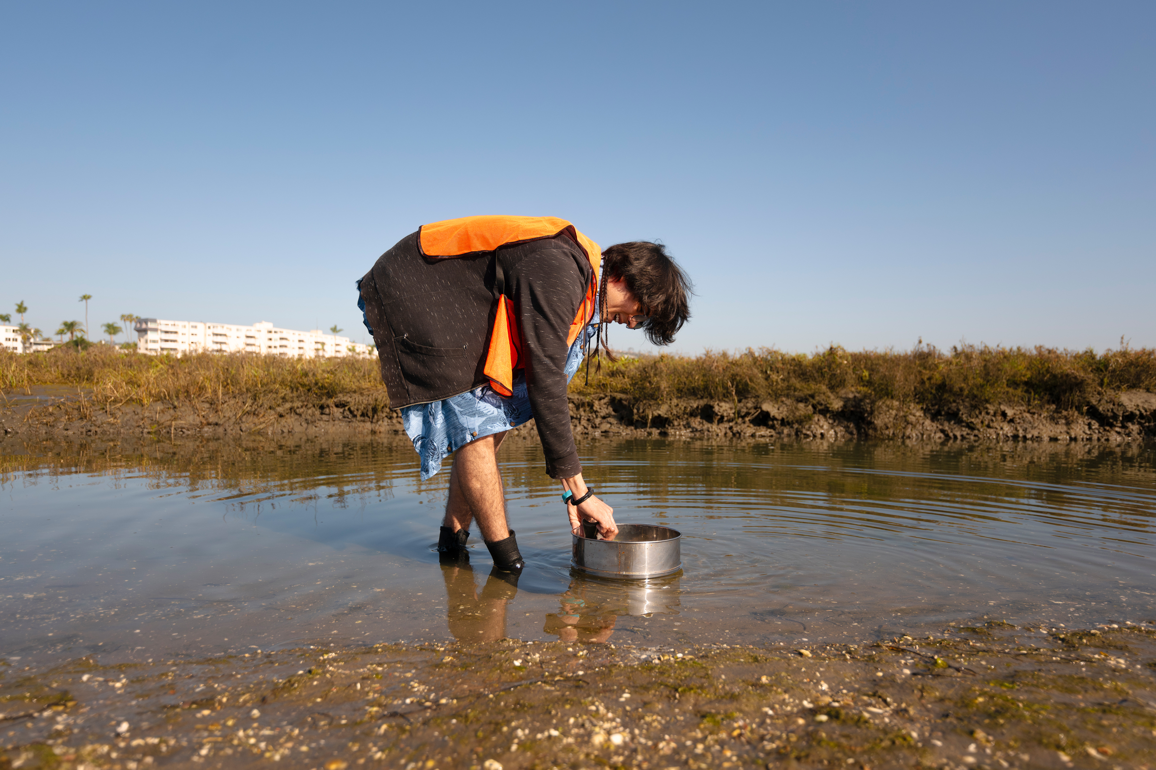 Person stands in water with bucket.