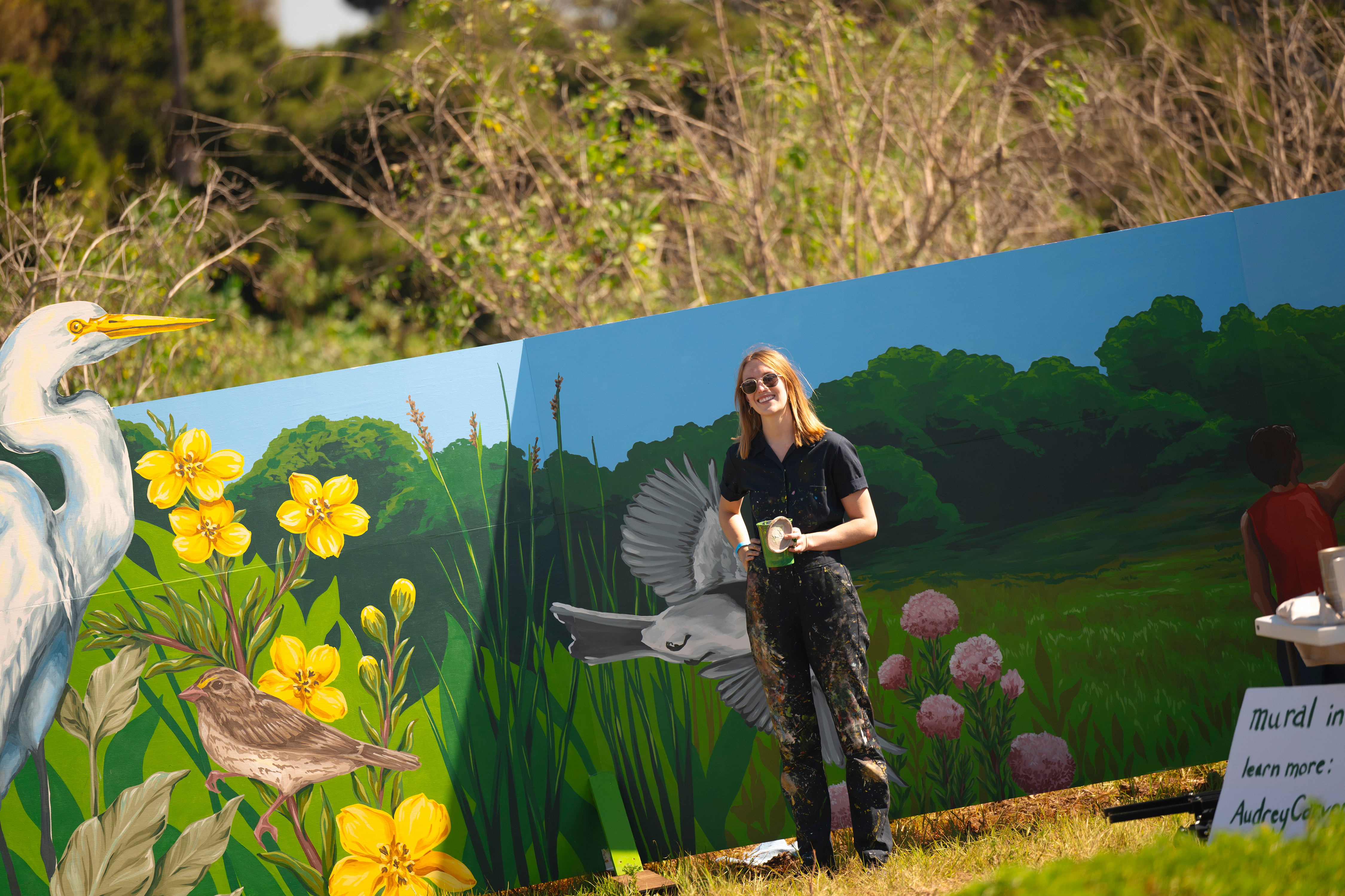 Woman stands in front of mural.
