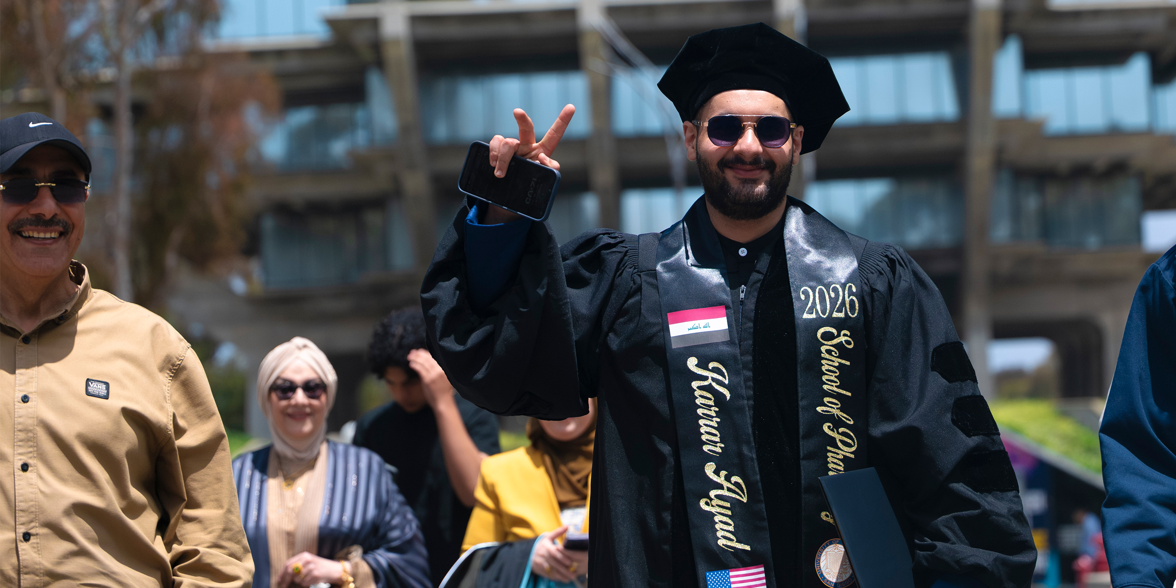Male graduate poses peace sign to the camera.
