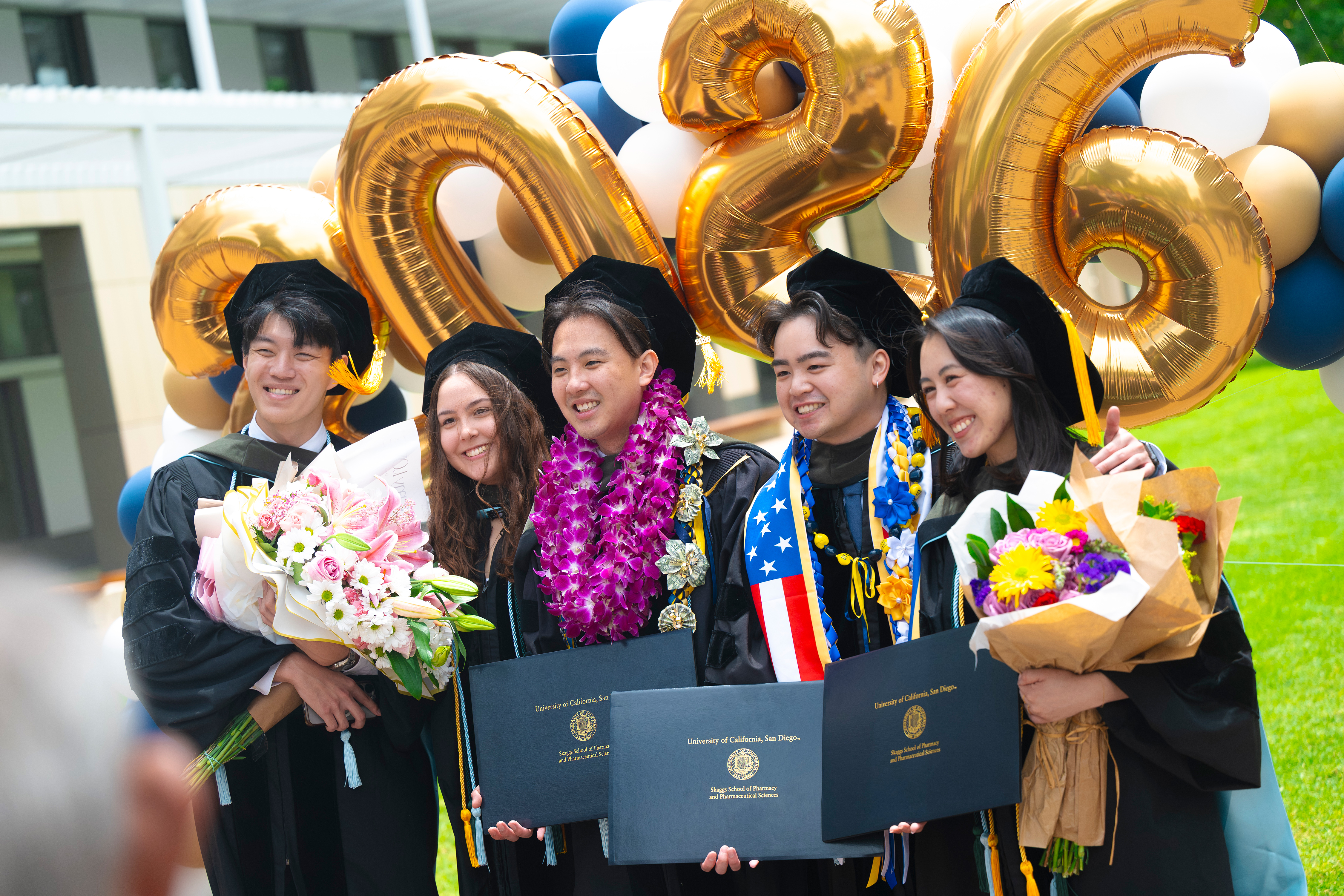 Group photo of friends holding their diploma, mementos and celebrating together.