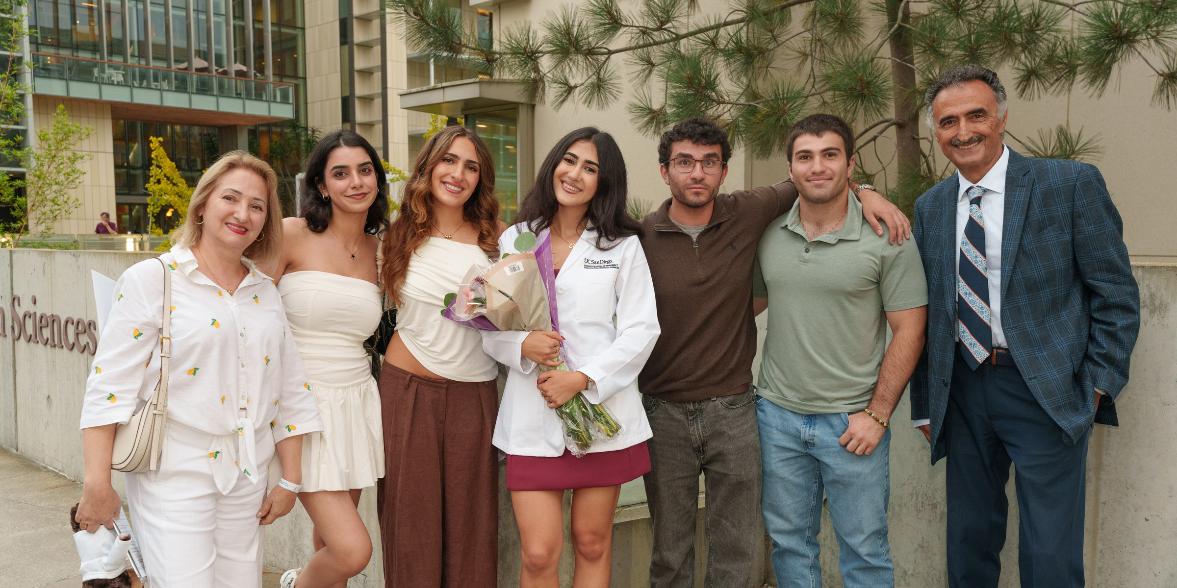 A family group photo with main female in center with her white coat jacket.