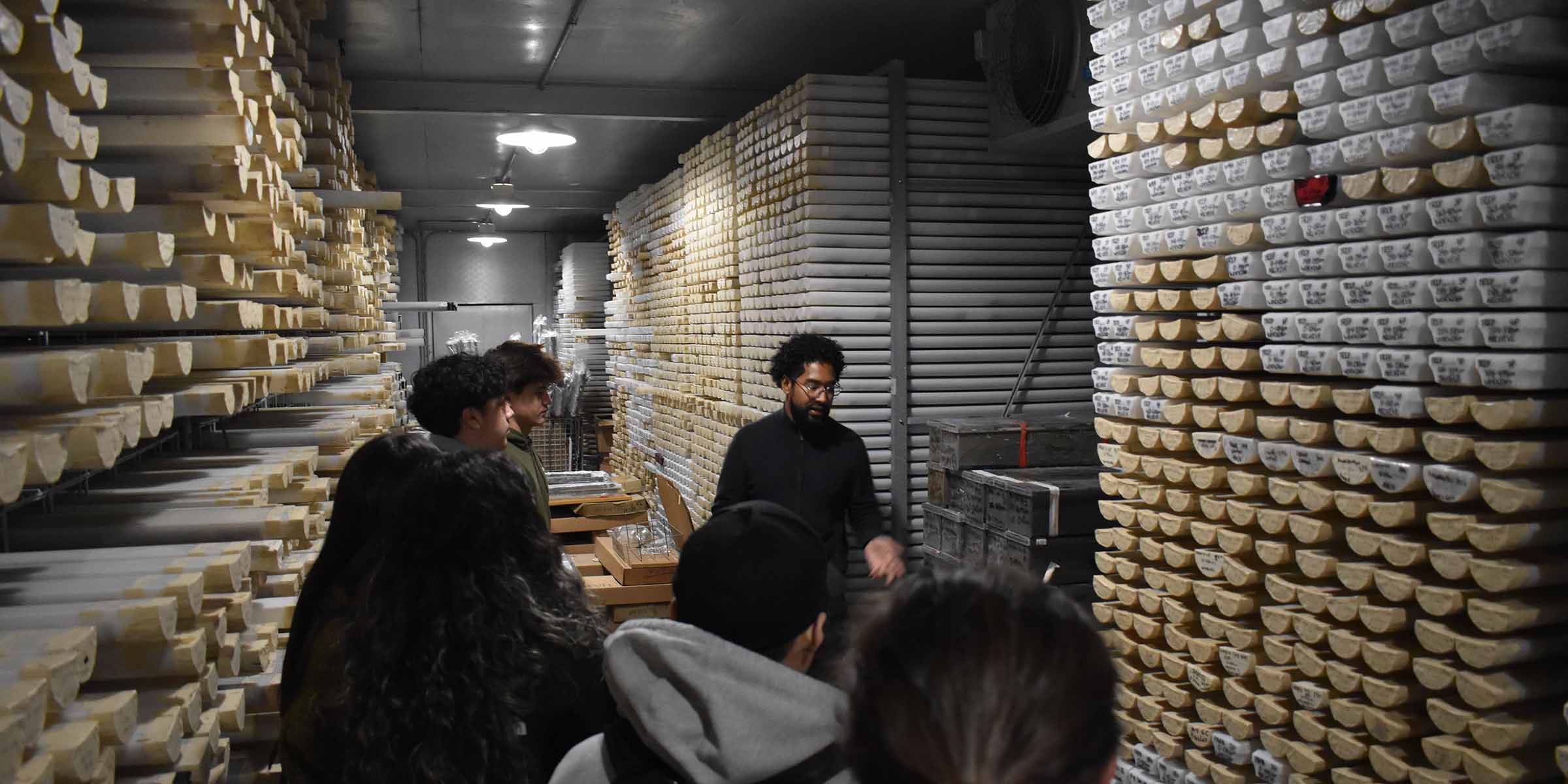A group of students and tour guide are surrounded by floor-to-ceiling core samples in the Scripps Geological Collections.