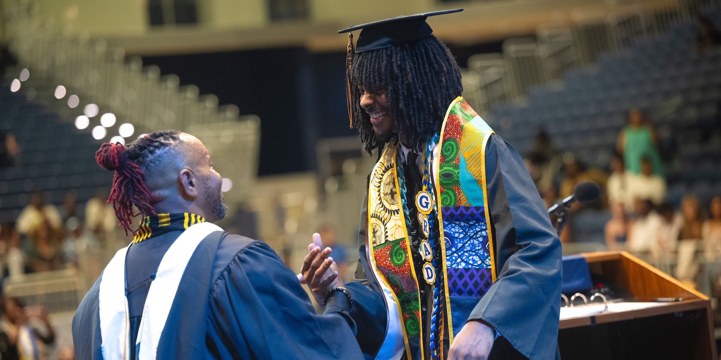 A graduate locking hands with the BRC director
