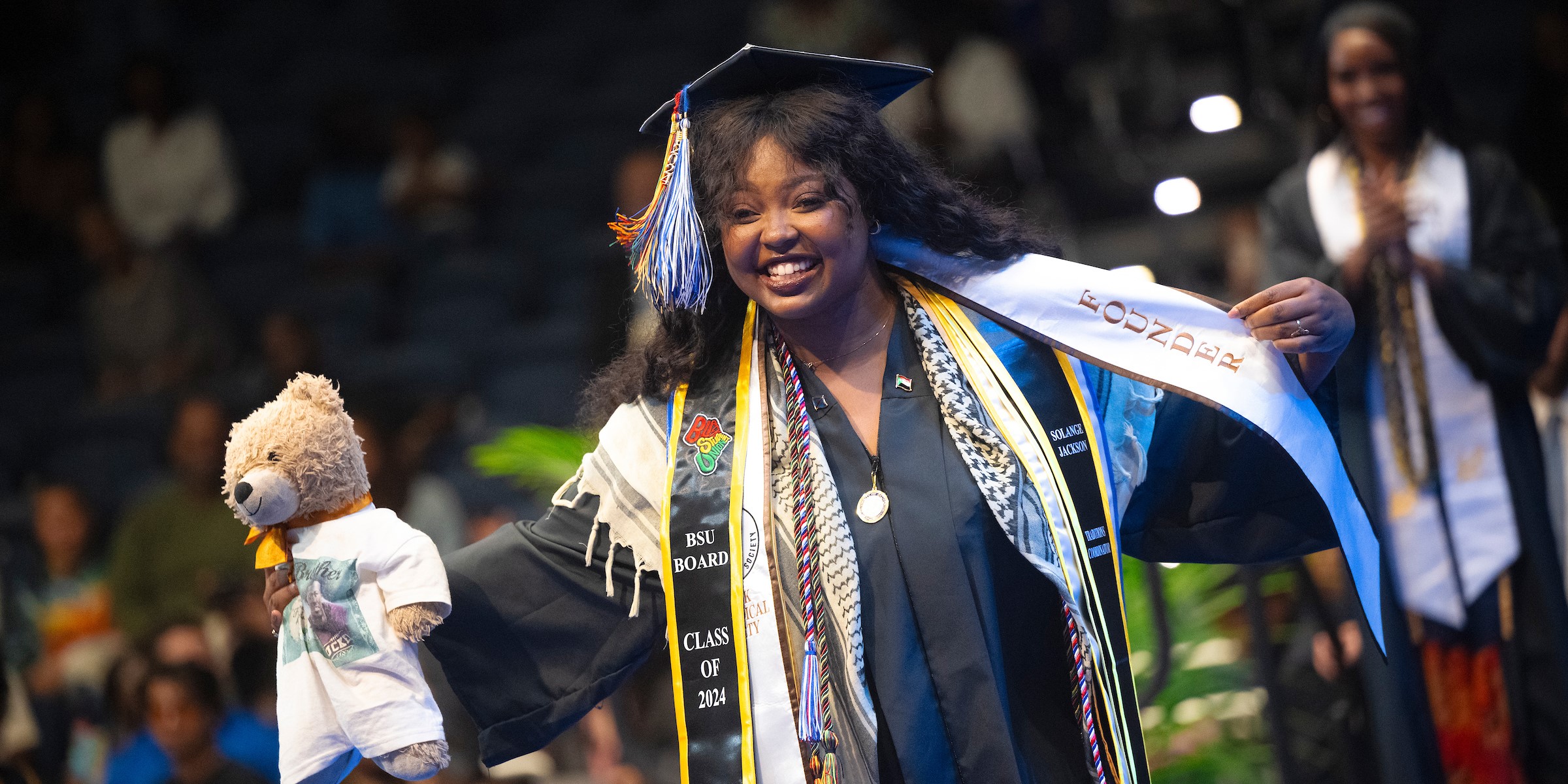 A graduate smiling walking across the stage