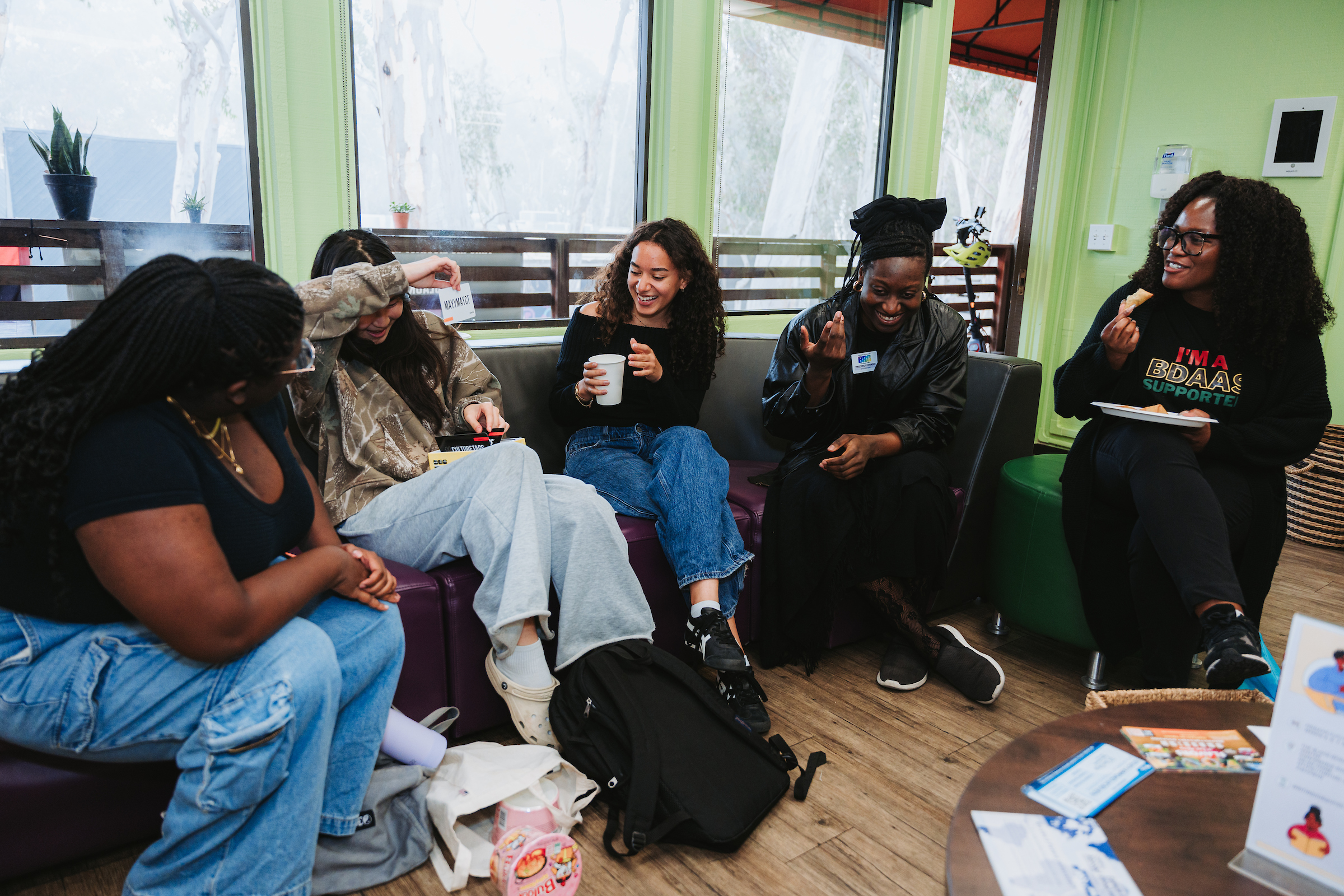 A group of people laugh while sitting on a couch