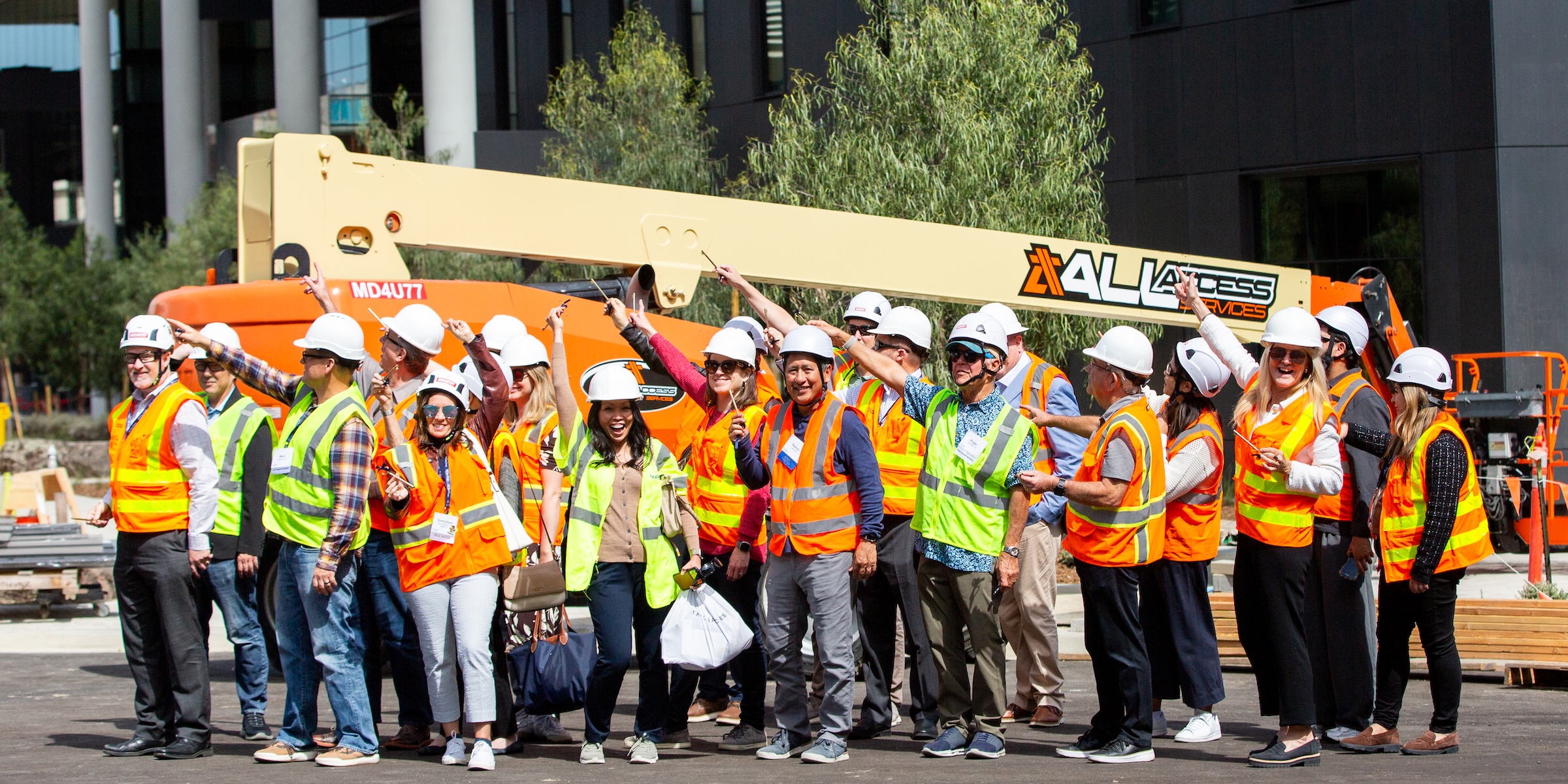 Group of people in front of a crane with hardhats holding golden keys