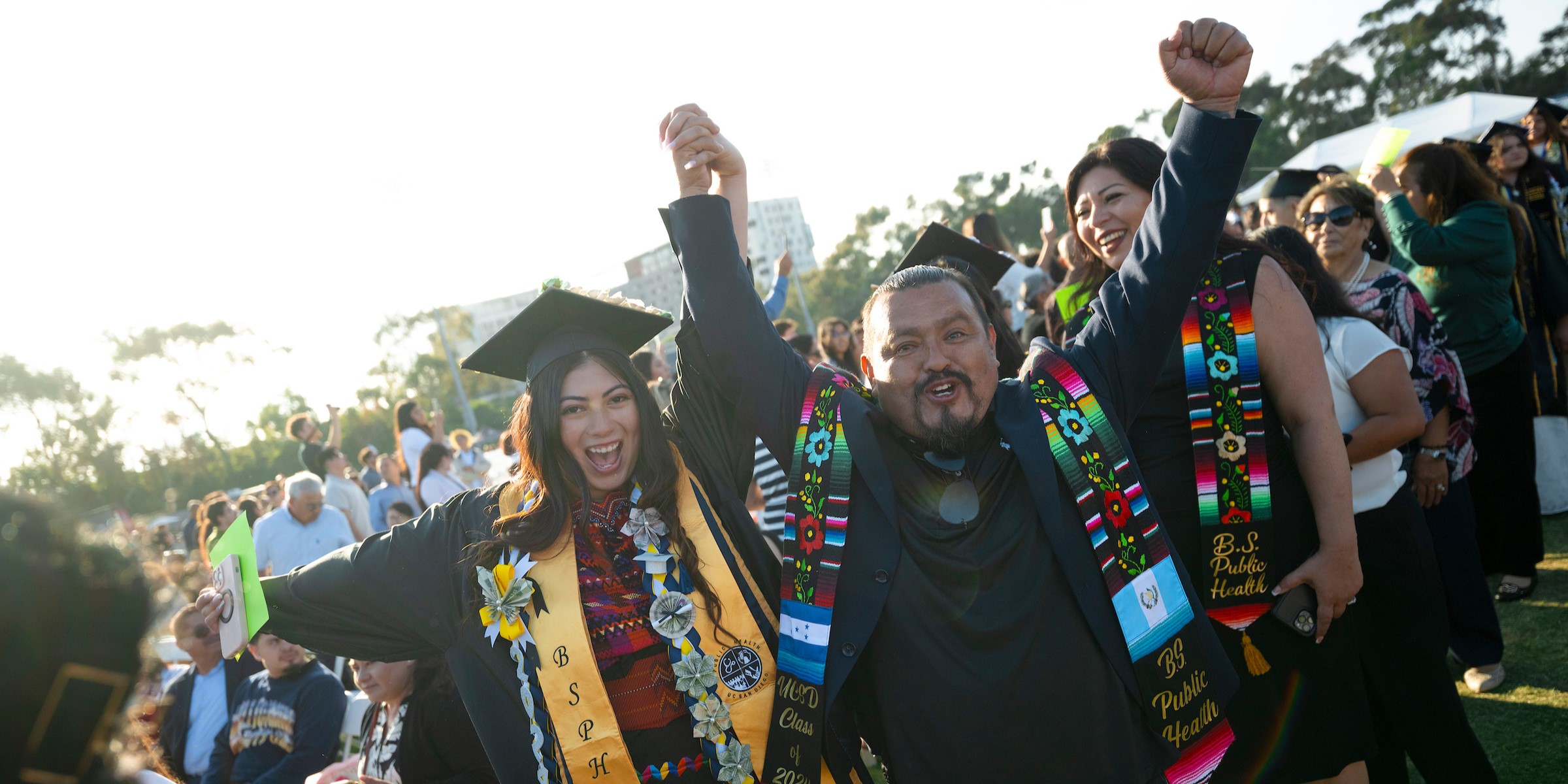 A parent and graduate holding hands raised in the air