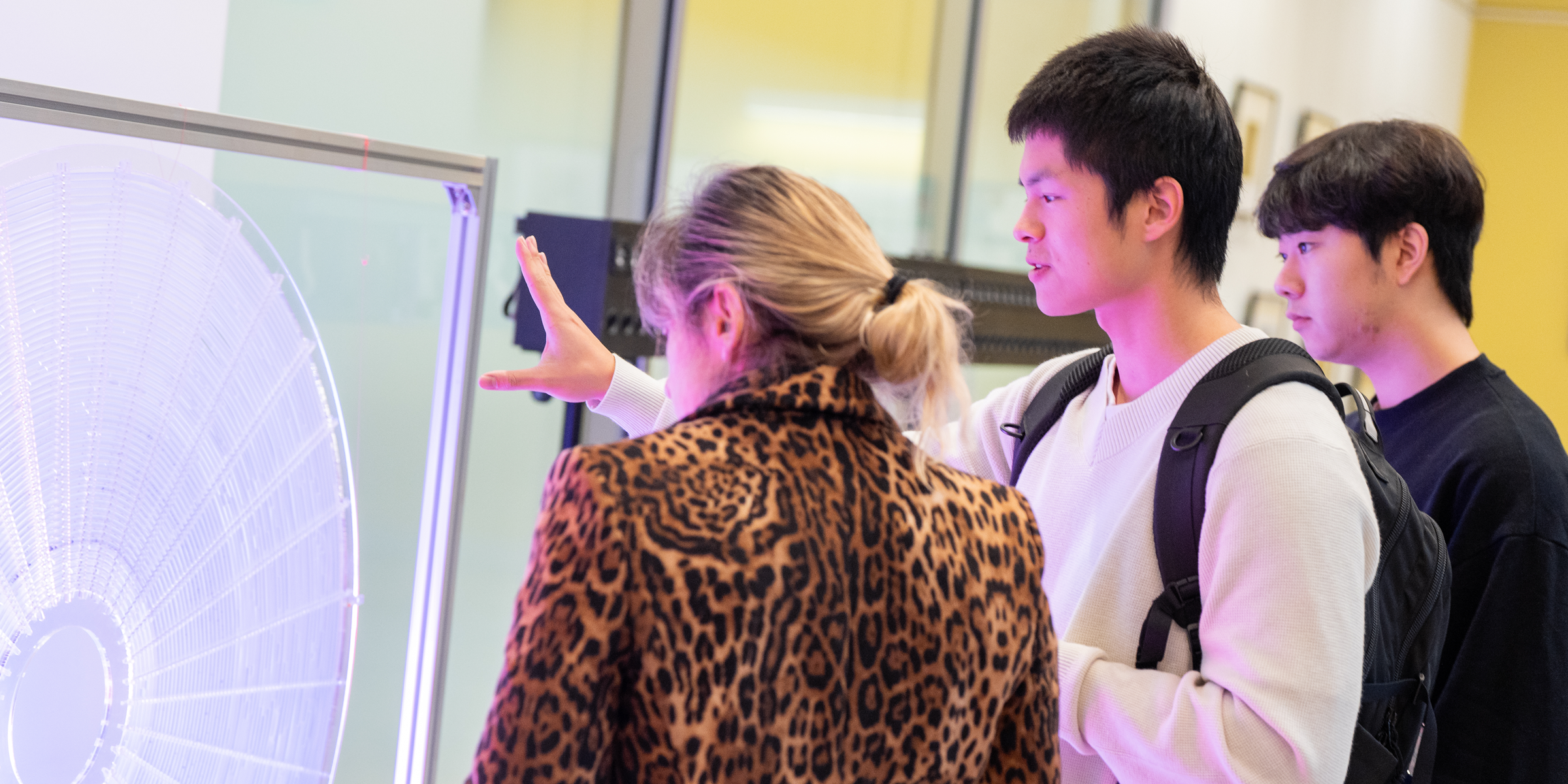 Two students discuss a sculpture with a faculty member