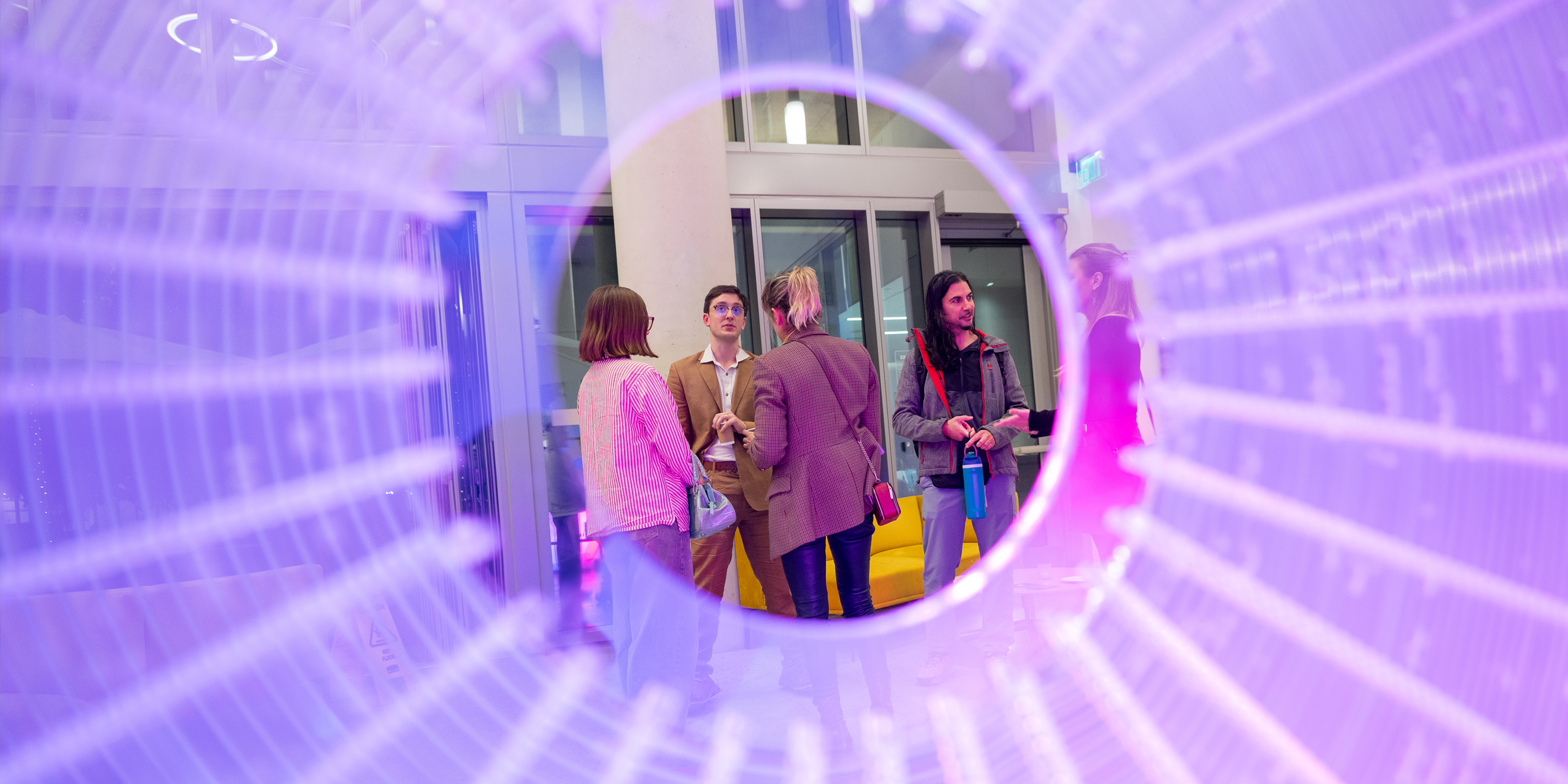 A group of people talk in front of a sculpture