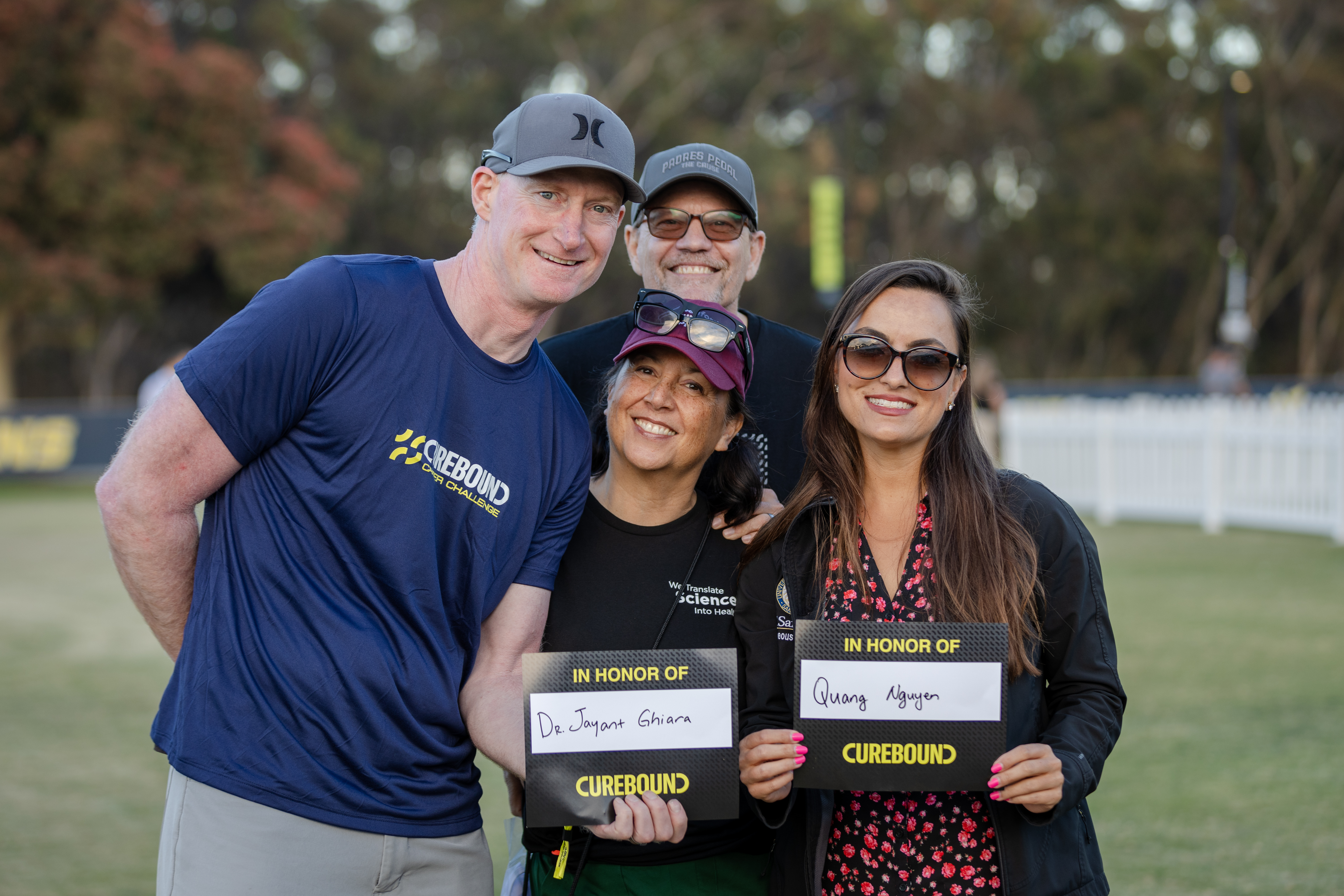 Four people holding signs with names on it 