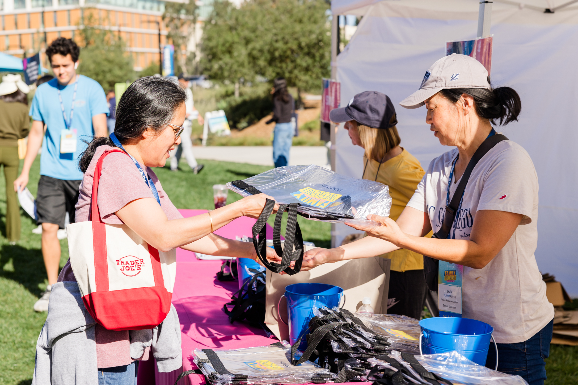 A volunteer hands a registrant a clear Family Weekend-branded tote bag