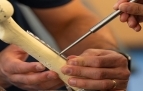 Slideshow: Close up photo of student using tools to place  a rod on a mock bone