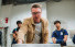 Slideshow: scientist in brown jacket talks to students in lab