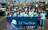 Slideshow: A large group of people wearing bright blue shirts stand behind a banner of Martin Luther King Jr