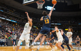 Slideshow: A basketball player wearing a blue uniform makes a reverse layup