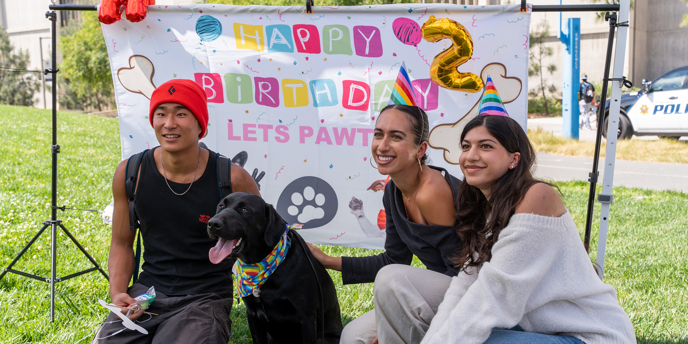 K-9 Diego poses with students in front of a birthday party backdrop.
