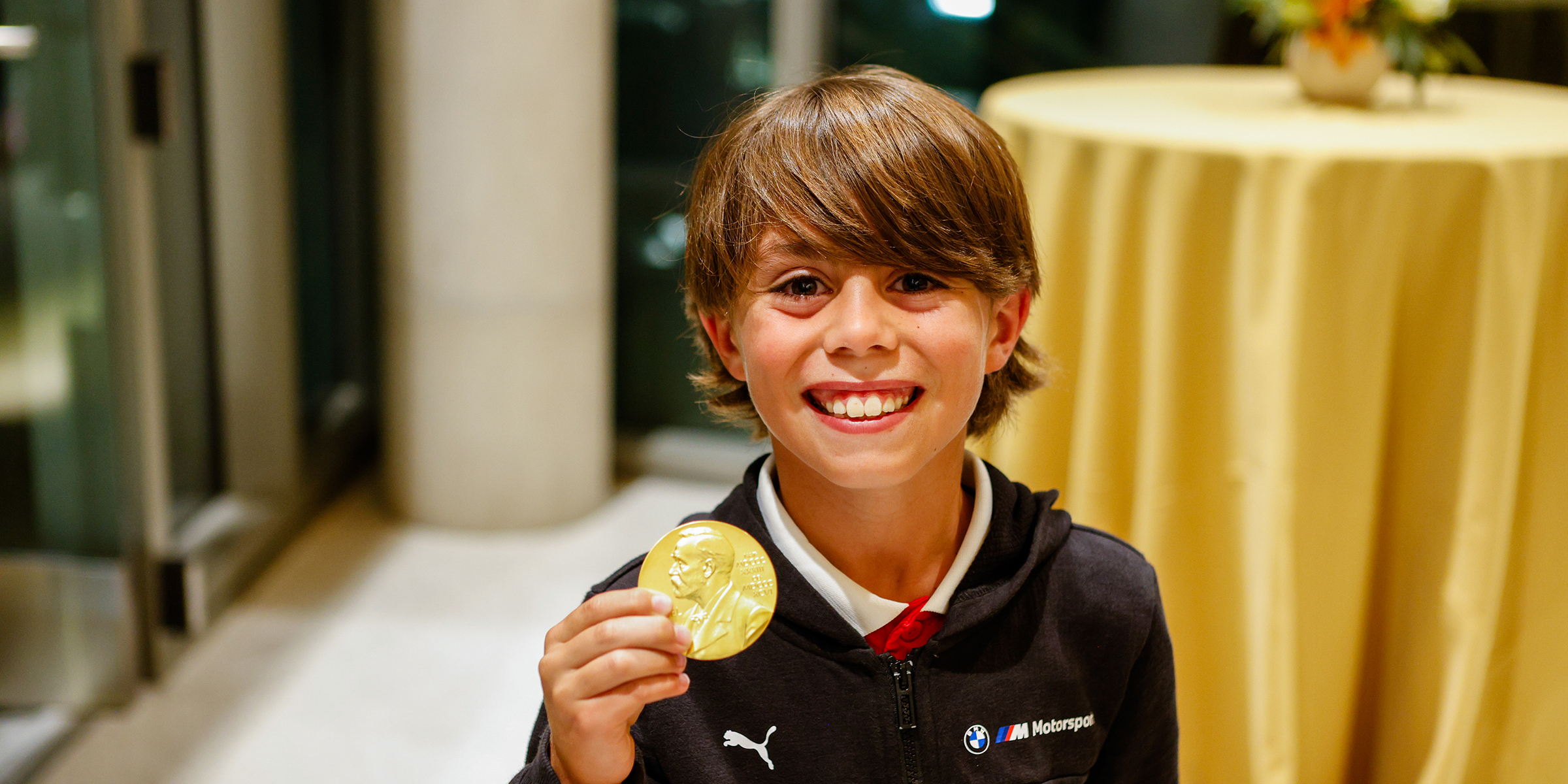 Young boy holding Nobel medal.