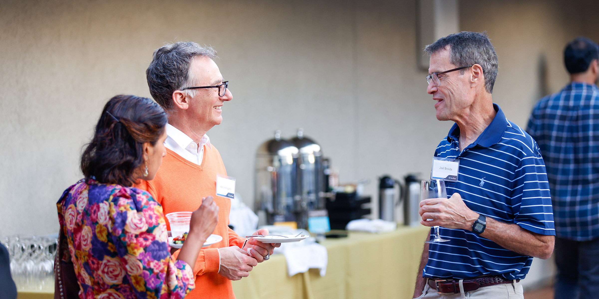 a woman and two men talking at reception