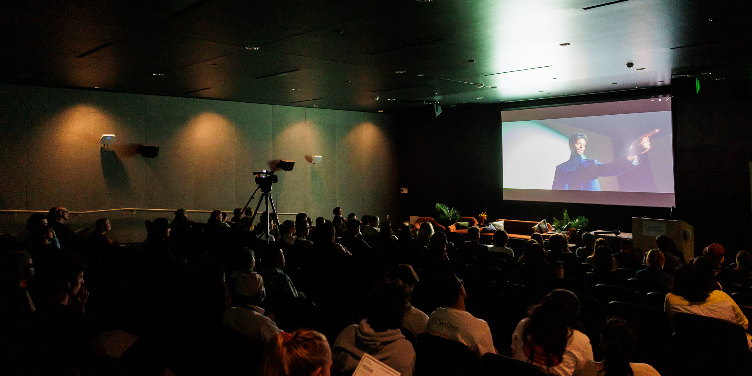 A dark auditorium where an audience is viewing a film.