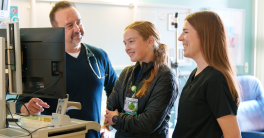 Three medical workers reviewing information on computer screen.