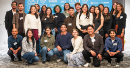 Group of people pose in front of a step and repeat with UC LEADS logo on it