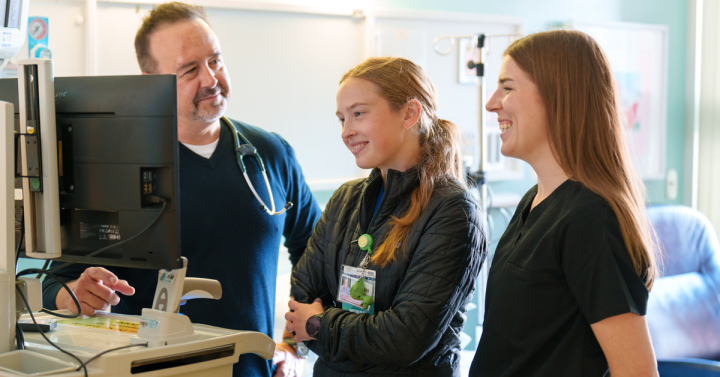Three medical workers reviewing information on computer screen.