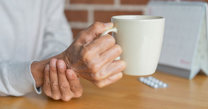 Hand holding a coffee cup is steadied by the other hand.