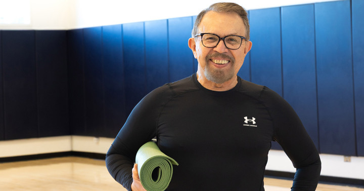 Arturo Galvez holds rolled-up yoga mat under arm