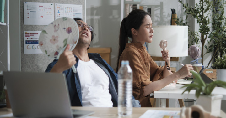 Workers looking annoyed in hot office. 