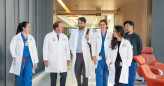 Photo of  six physicians walking towards the camera, smiling and talking to one another.