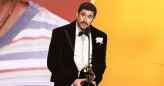Bad Bunny holding Grammy trophy and speaking into microphone