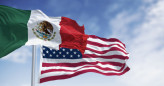 Mexico and US national flags waving on a clear day. Tricolor of green, white, and red with national coat of arms in the center of the white stripe. 3D illustration render. Rippled textile. Selective focus